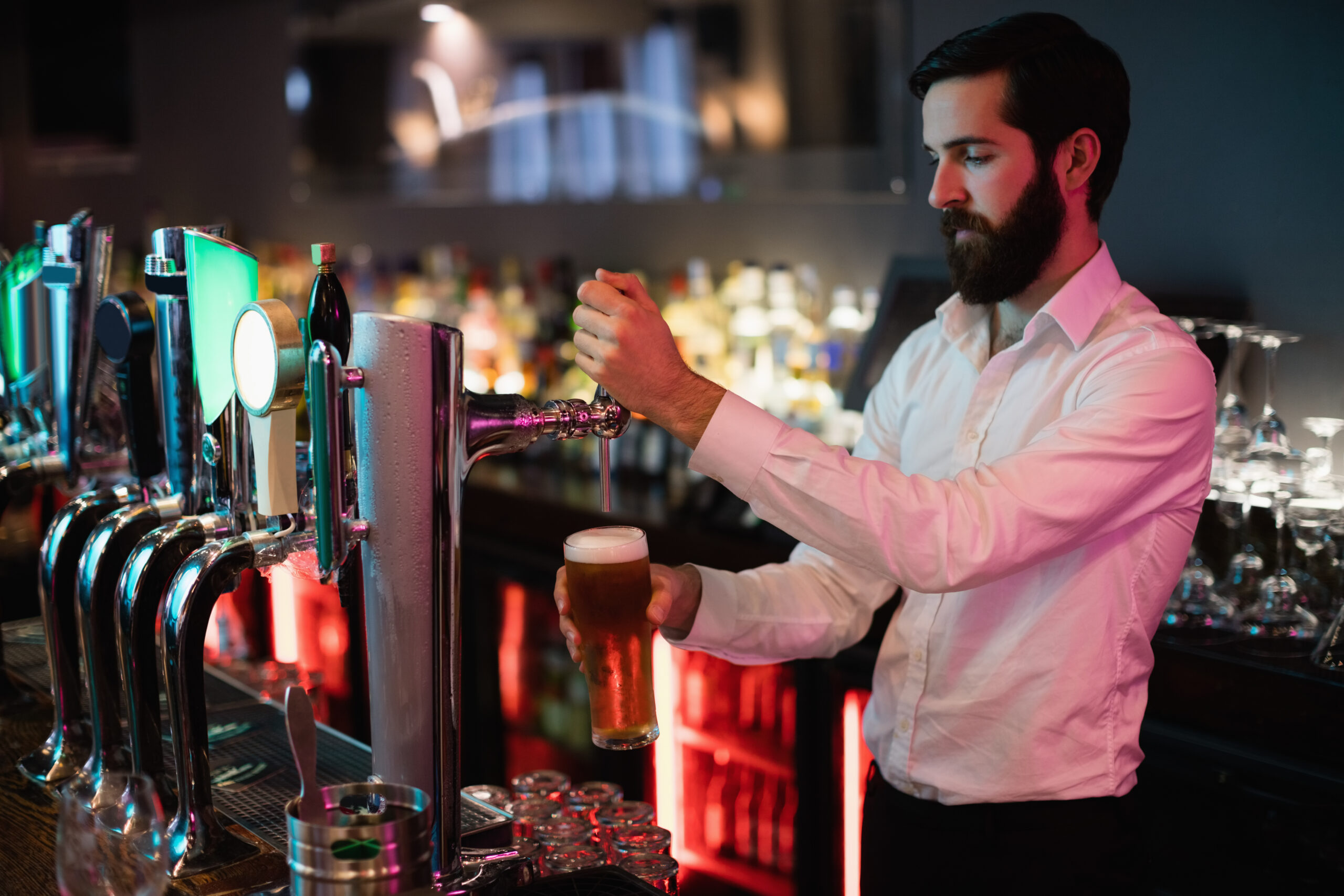 Bartender filling beer from bar pump at bar counter