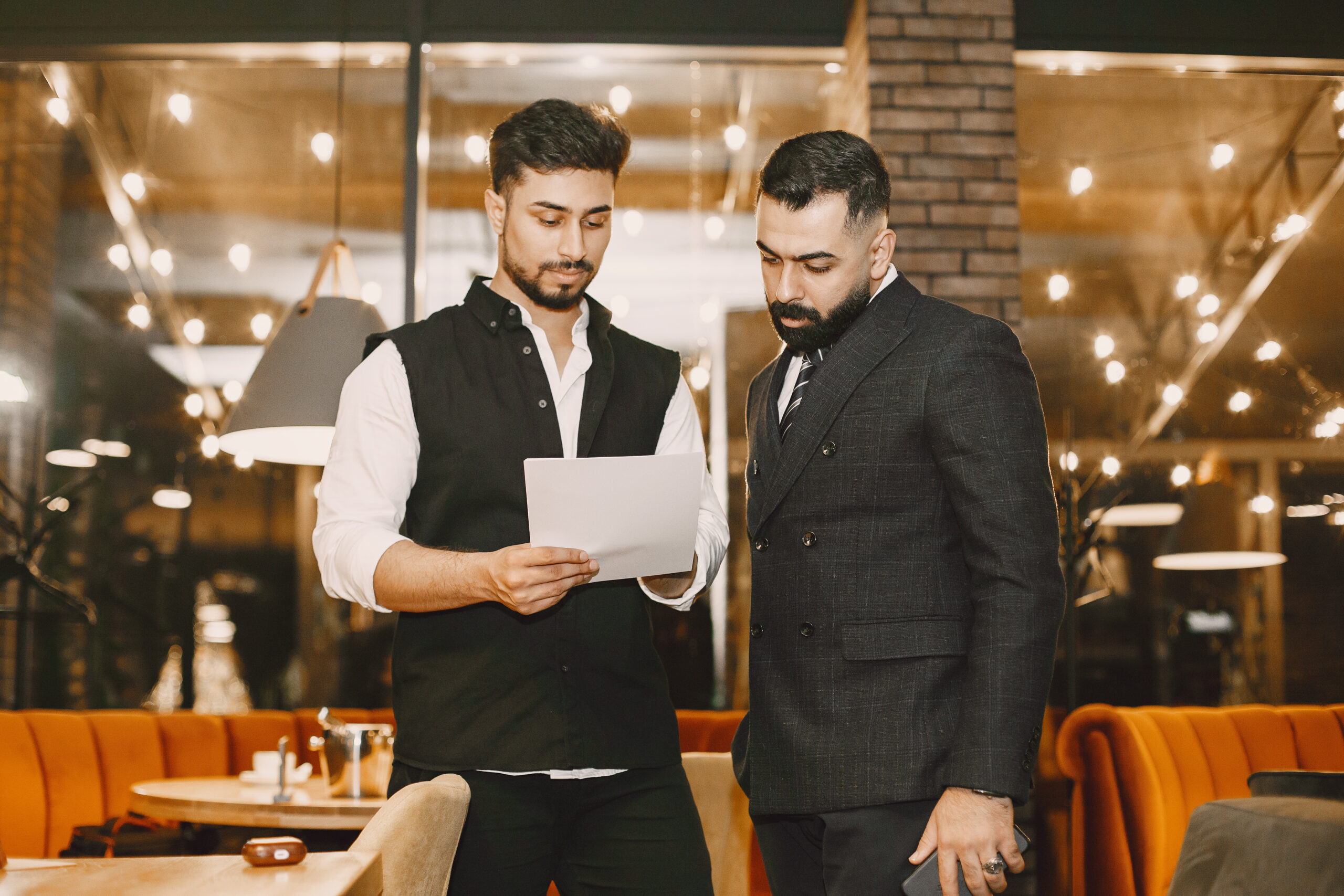 Handsome man in a black suit. Businessmen working in a cafe. People stands and looks in a documents.