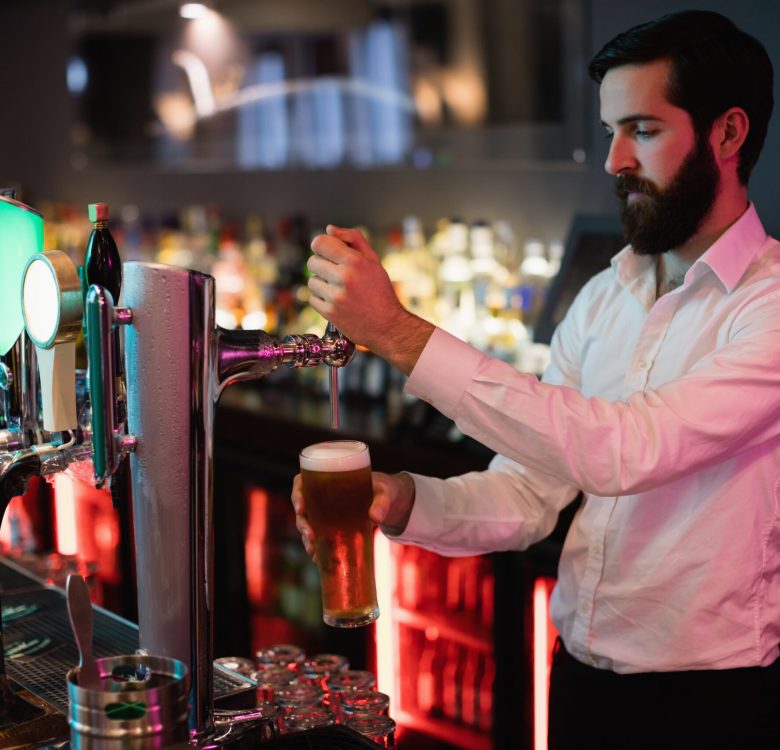 Bartender filling beer from bar pump at bar counter